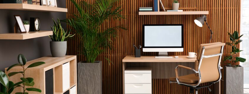 Bequemer Arbeitsplatz mit Computer in der Nähe einer Holzwand im stilvollen Innenraum. Home-Office-Design
