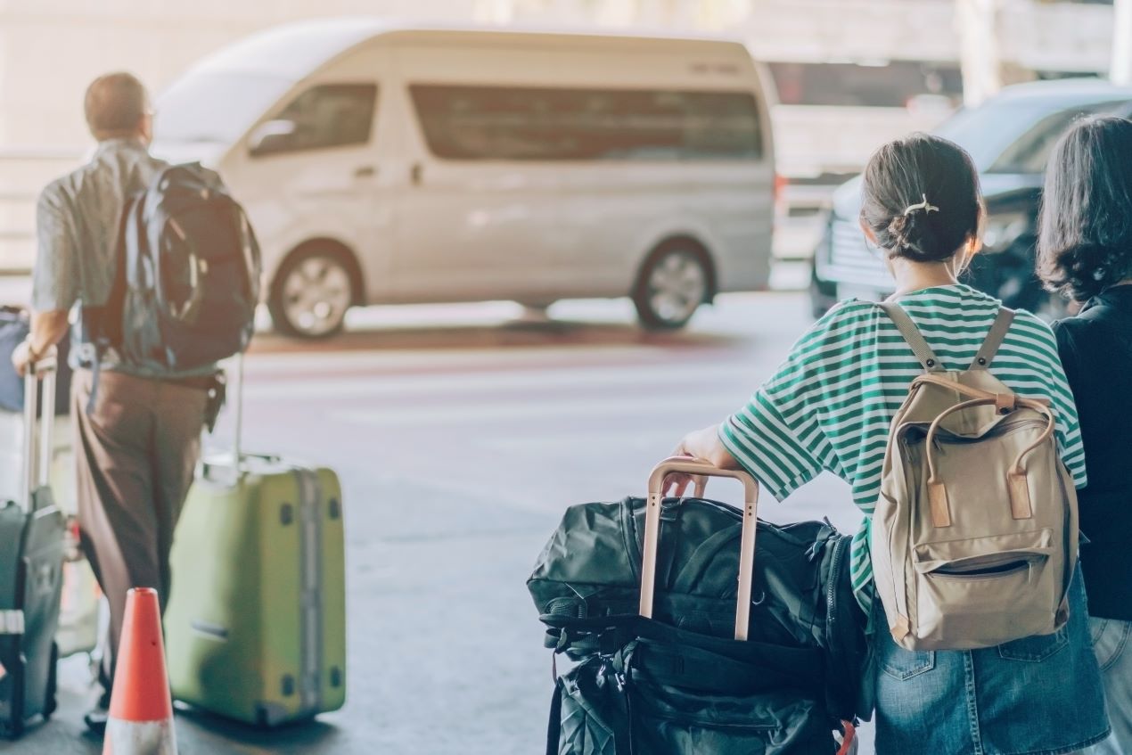 Reisende mit Koffern warten auf einen Shuttlebus – Parken Flughafen Nürnberg mit Transfer zum Terminal für eine entspannte Anreise.