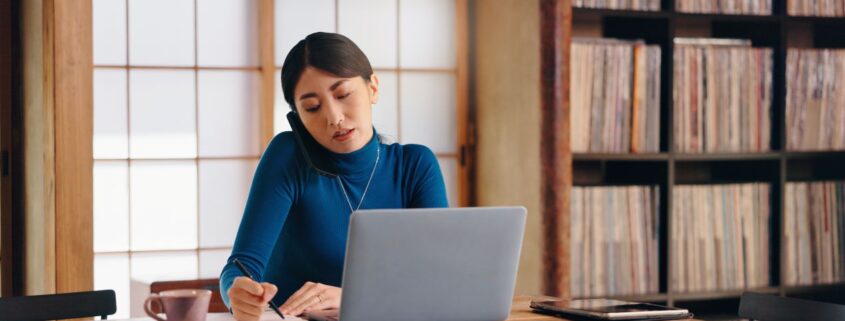 Frau am Schreibtisch mit Laptop und Notizblock – konzentrierte Textarbeit für das Buch Lektorat in gemütlicher Umgebung.