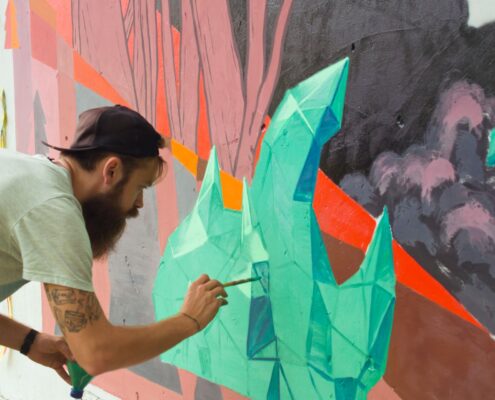 Graffiti Sprayer malt präzises Wandbild mit Pinsel