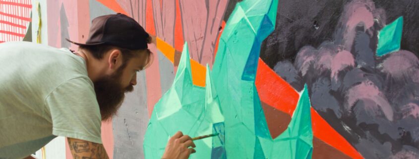 Graffiti Sprayer malt präzises Wandbild mit Pinsel