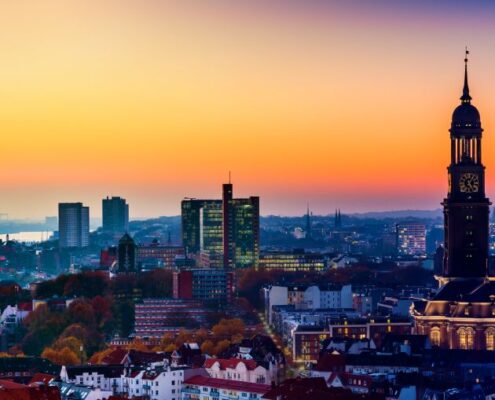 Stimmungsvolle Skyline von Hamburg mit Elbe und Michel bei Sonnenuntergang, symbolisch fuer Escort Hamburg
