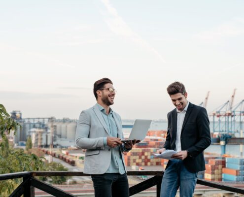 Zwei Männer mit Laptop und Unterlagen auf Dachterrasse