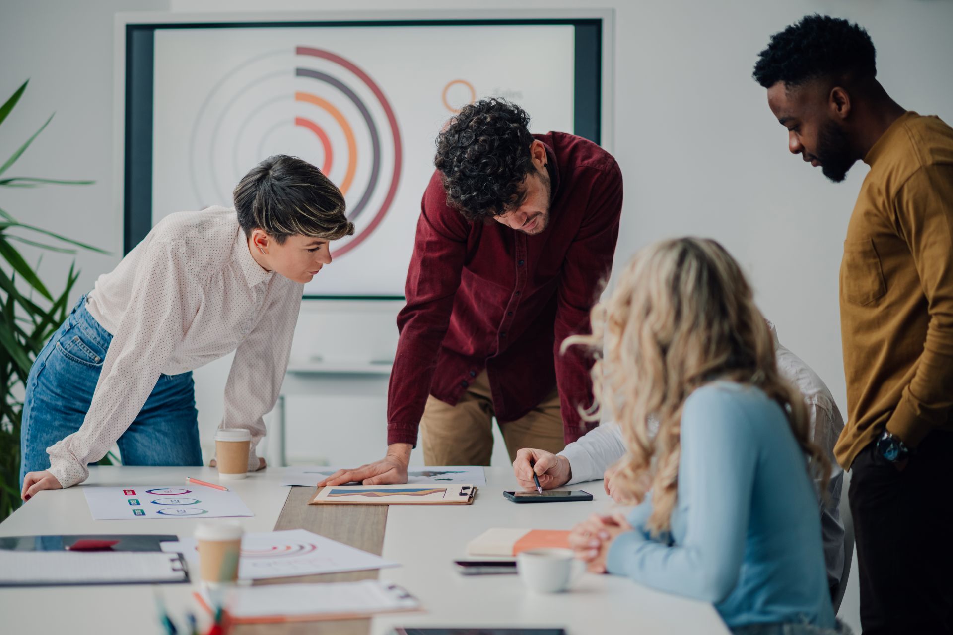 Vier Personen arbeiten gemeinsam an einem Projekt mit Laptop und Diagrammen im Buero – Darstellung fuer digitale Teamarbeit und transparente BueroService Preise